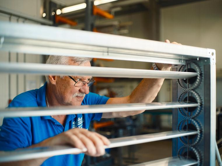 Ein älterer Northoff-Mitarbeiter prüft die Lamellen eines Lüftungselements.