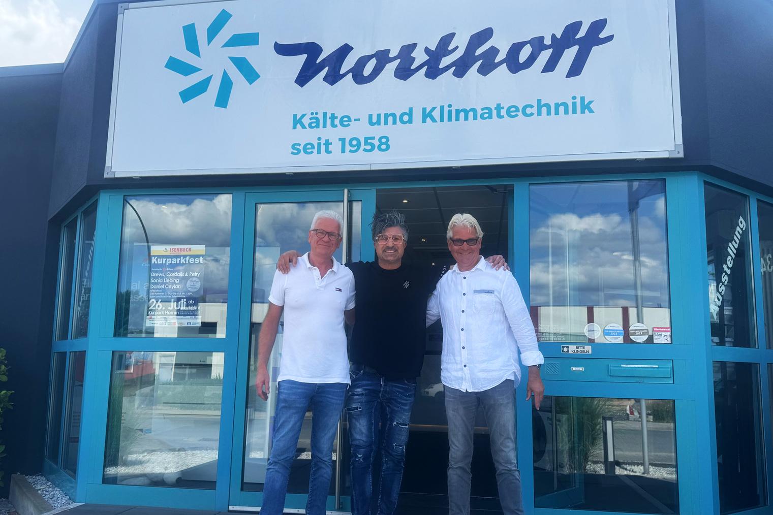 Drei Männer stehen im Eingangsbereich des Northoff Firmengebäudes mit Logo.