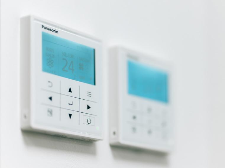 Zwei weiße Panasonic Thermostate an einer Wand, einer zeigt "24° Soll-Temp".