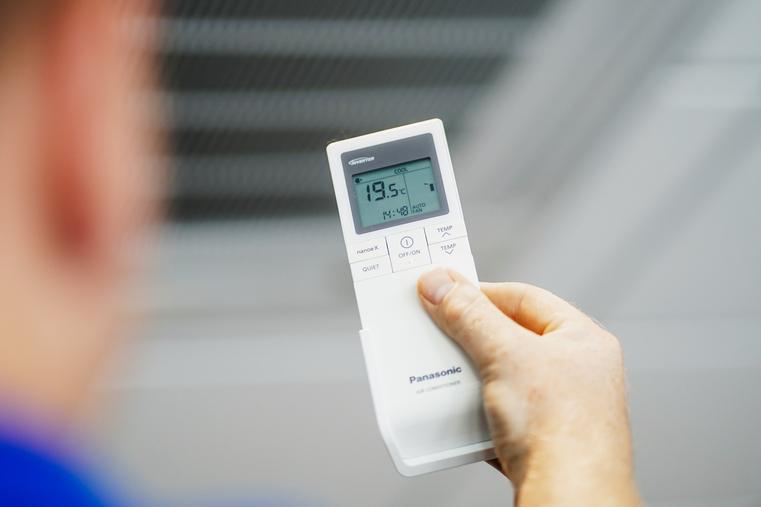 Hand hält eine Panasonic Fernbedienung für Klimaanlagen, zeigt 19.5°C.