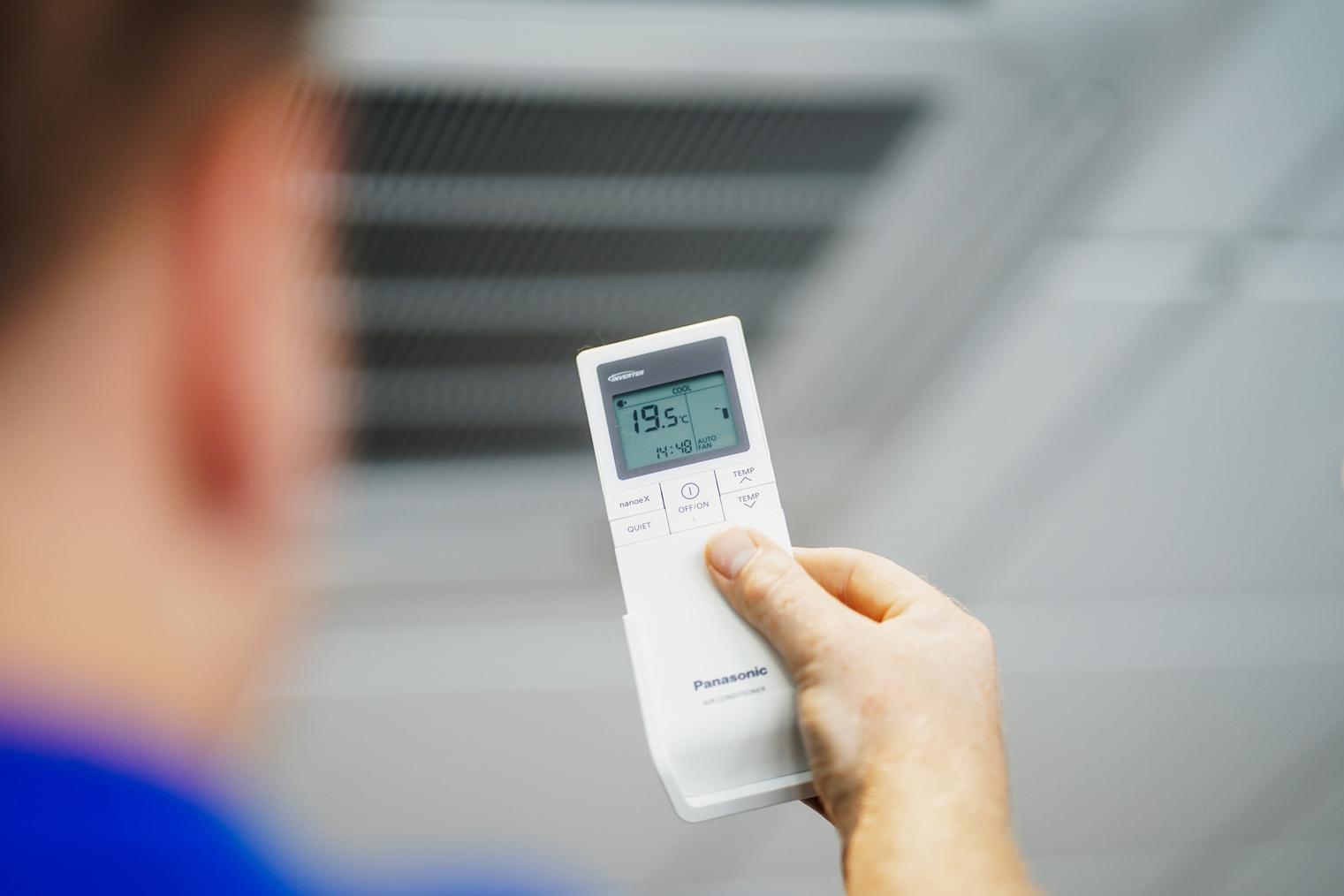 Hand hält eine Panasonic Fernbedienung für Klimaanlagen, zeigt 19.5°C.