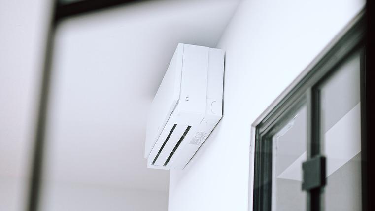 Weiße Klimaanlage an einer Wand in einem Raum, seitlich von einer Tür.