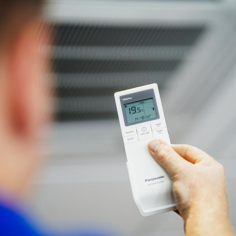 Hand hält eine Panasonic Fernbedienung für Klimaanlagen, zeigt 19.5°C.