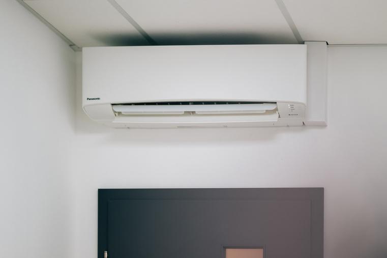 Weiße Panasonic Wandklimaanlage mit geöffneter Klappe, installiert im Innenraum.