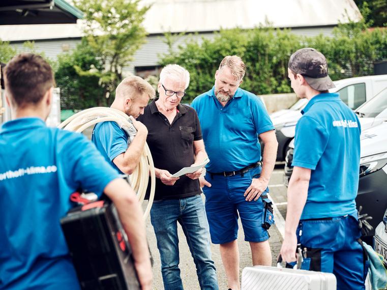 Vier Northoff Techniker in blauen Firmen-Shirts und ein Kunde besprechen Pläne im Freien.