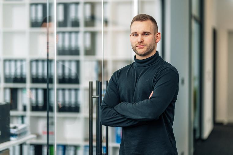 Geschäftsführer Kevin Northoff blickt im modernen Büro in die Kamera.